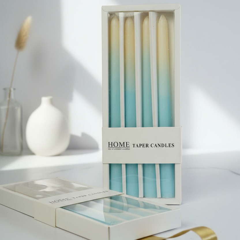 Set of home taper candles in a box on a white surface with a vase in the background